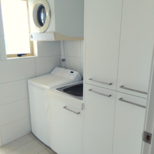 Laundry room with wall of washing machine positioned next to cabinet with laundry sink followed by two laundry cabinets