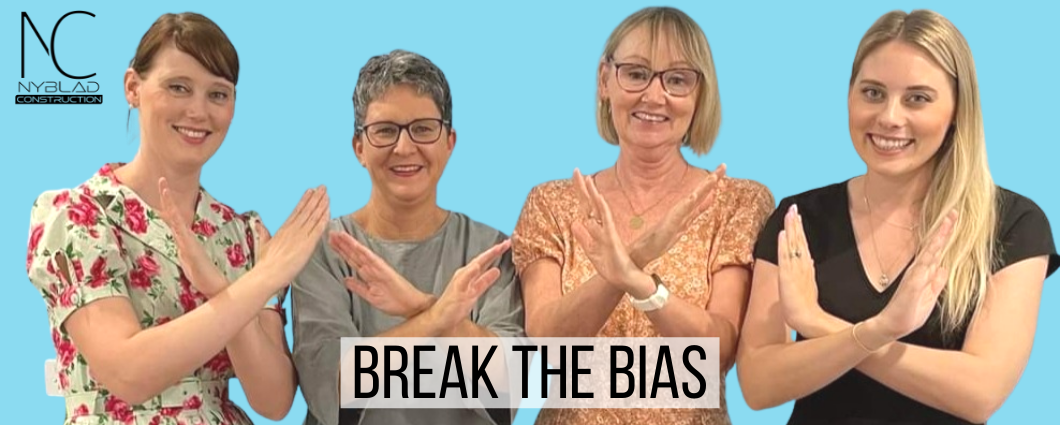 4 female team members standing with arms crossed in front of them in the official "break the bias" pose for international women's day