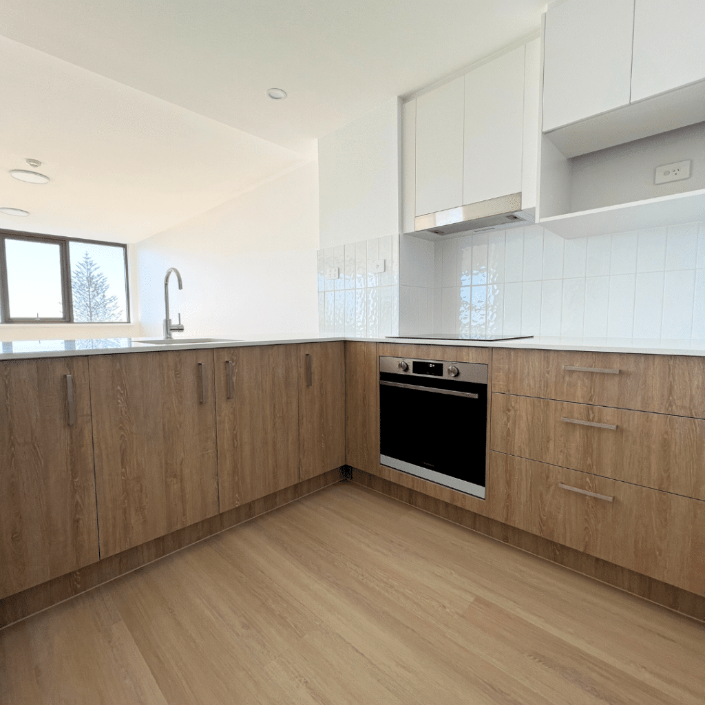 kitchen with two-tone cabinetry (white on overheads and oak-coloured lower cabinets) paired with textured white splashback tiles