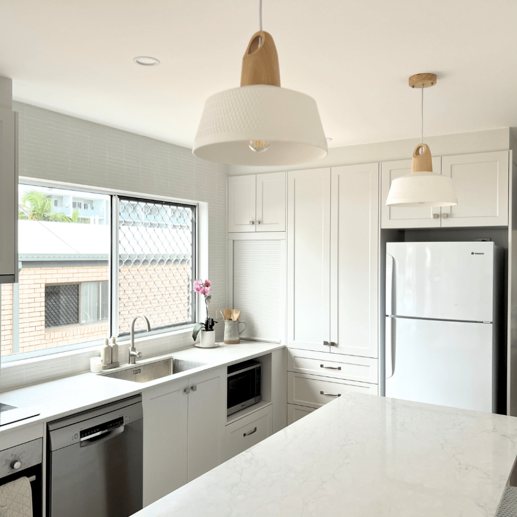 white kitchen with shaker profile cabinets and statement pendant lights