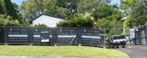 fence with Nyblad Construction branding erected around a house that is being renovated.